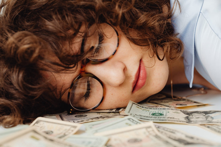 Foto van een vrouw die slaapt op een paar bankbiljetten